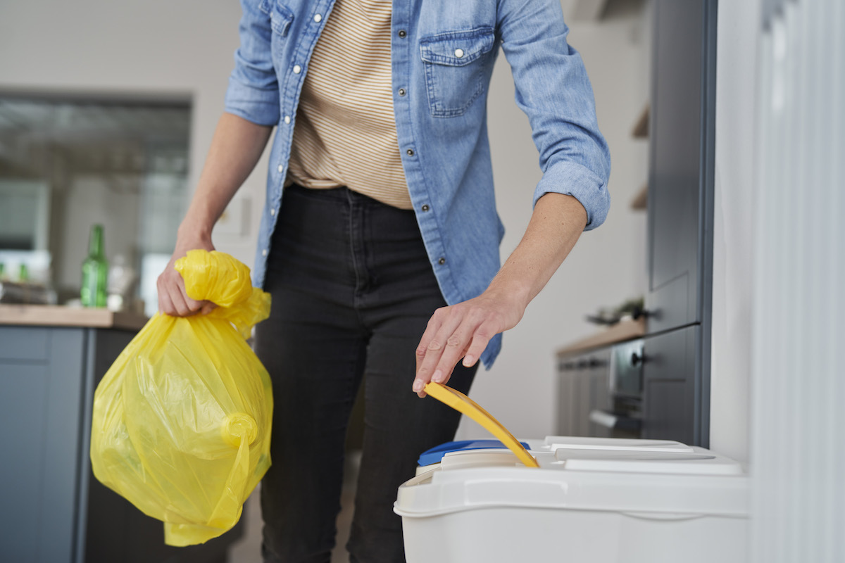 Persona deposita residuos plásticos en un cubo